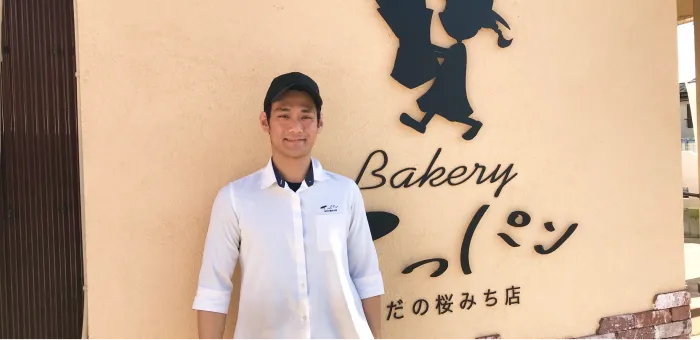 てっパンの看板の前に立つ店主